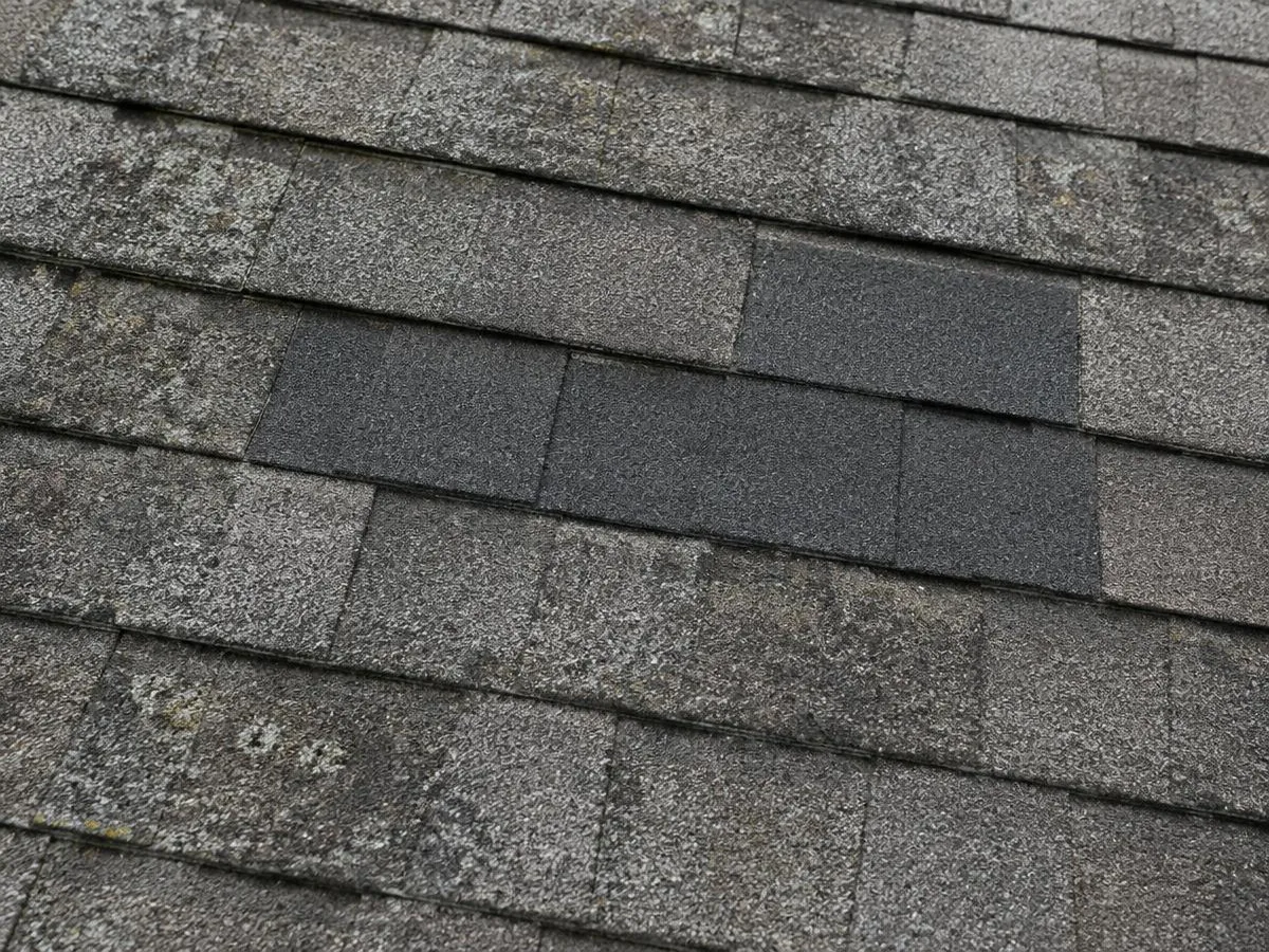 A small patch of new shingles on an older weathered roof