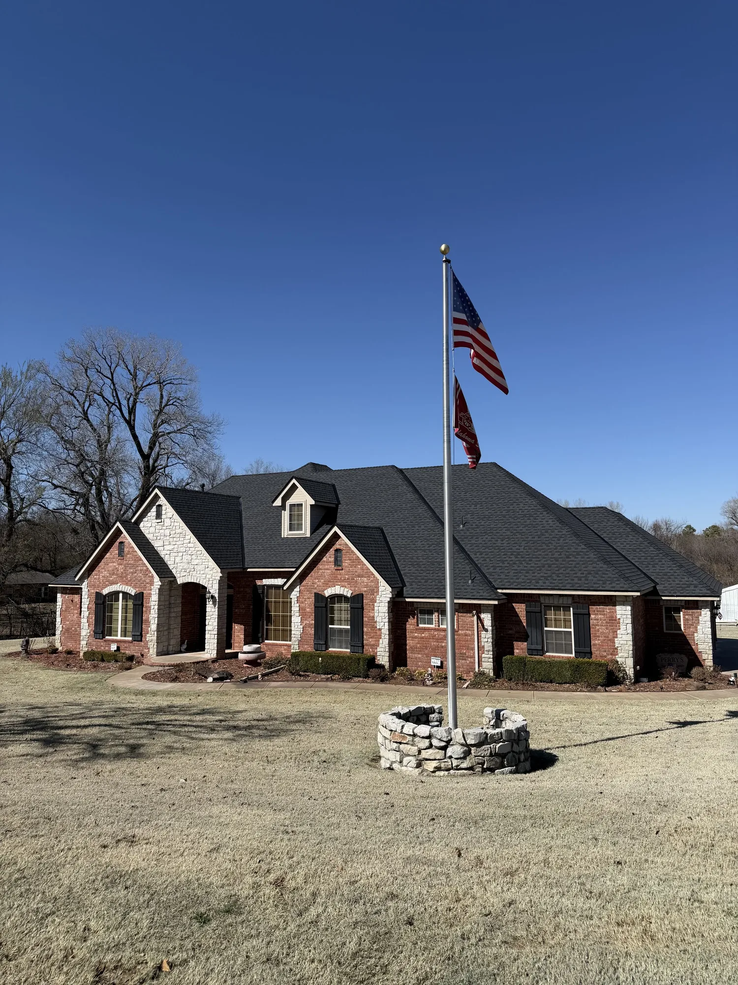 Brick ranch home with a new dark shingle roof and a flagpole out front