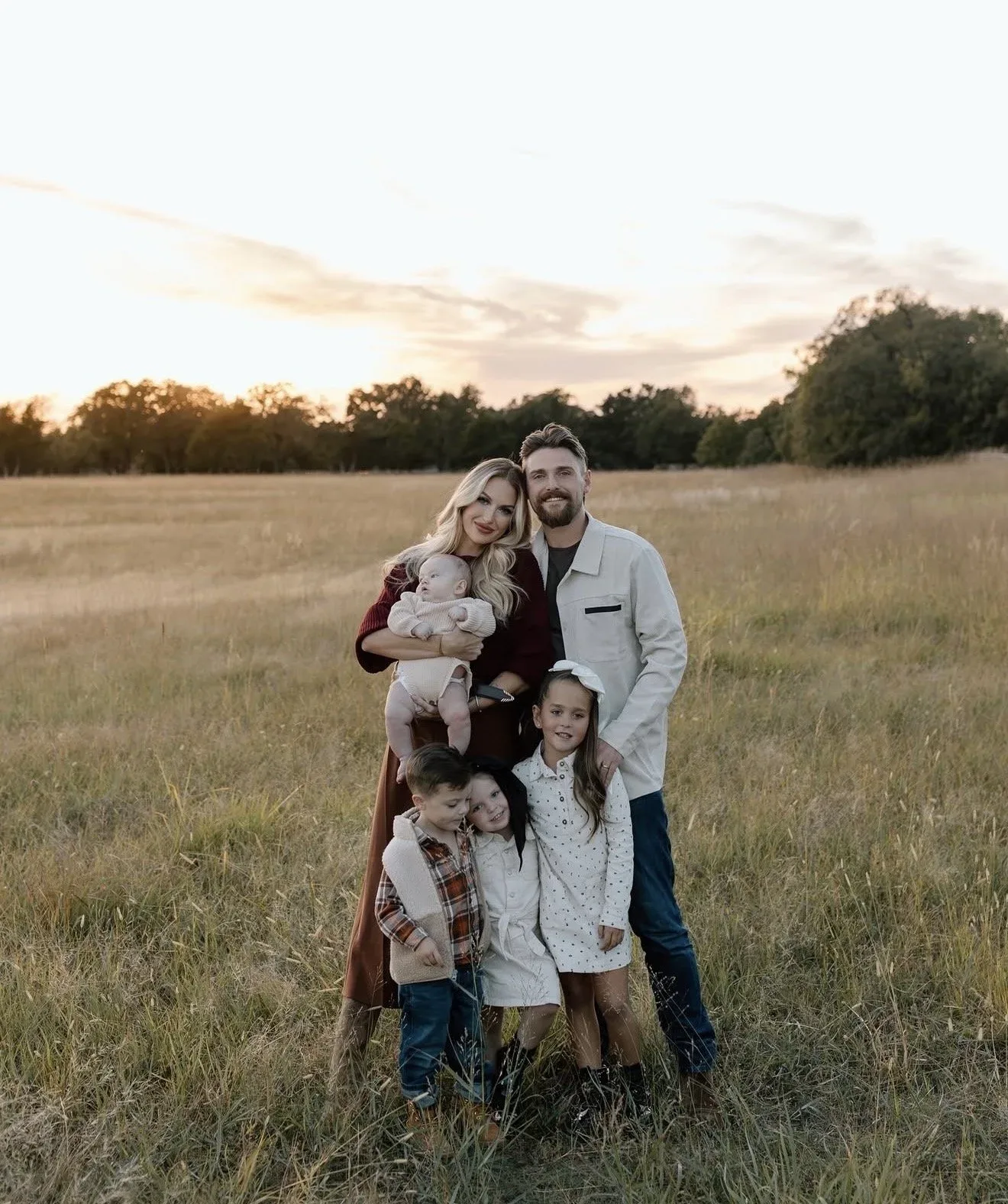 Tusk Roofing owner Colton Miller and his family in a field at sunset