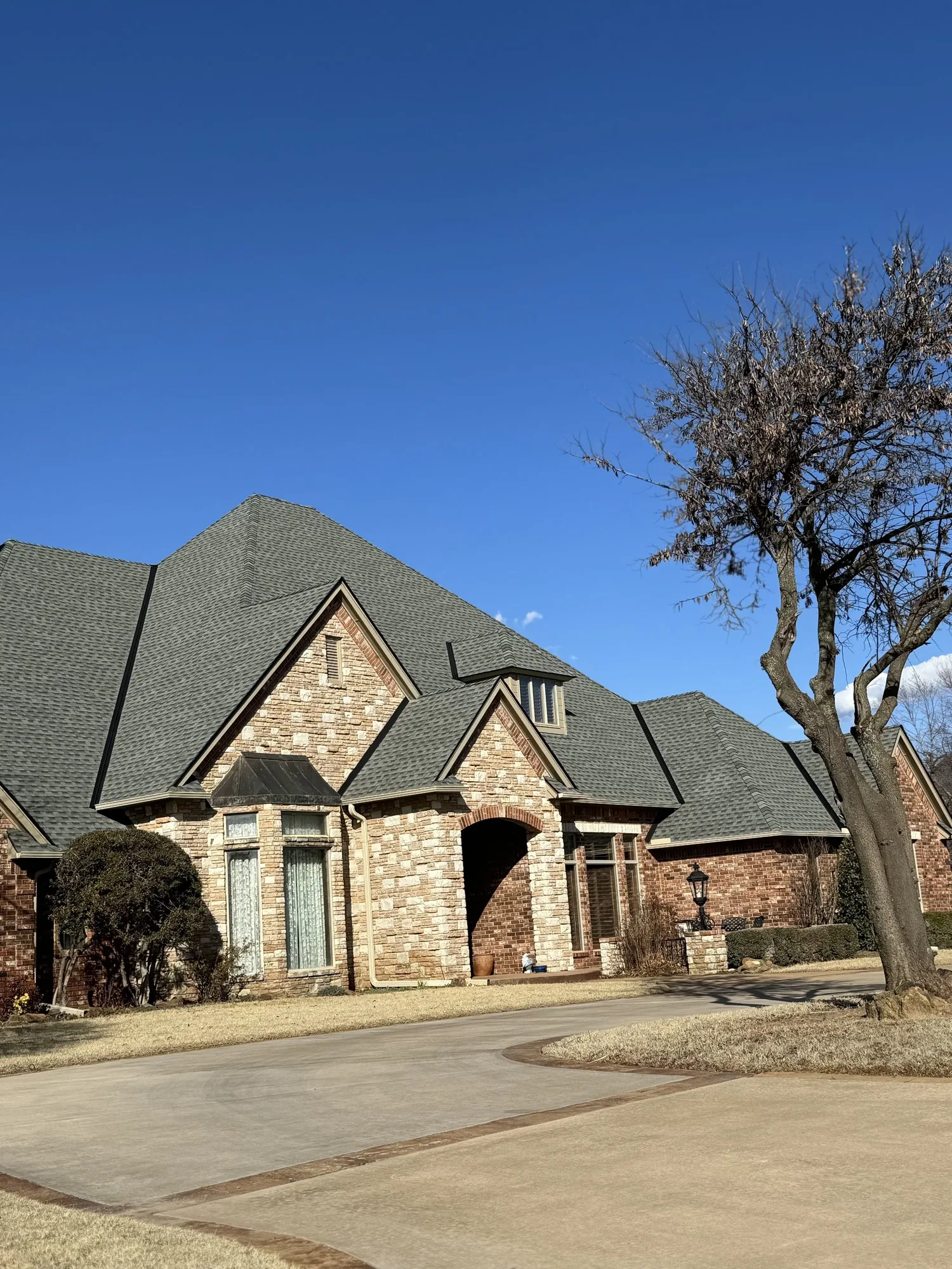 Stone and brick home with a new gray shingle roof
